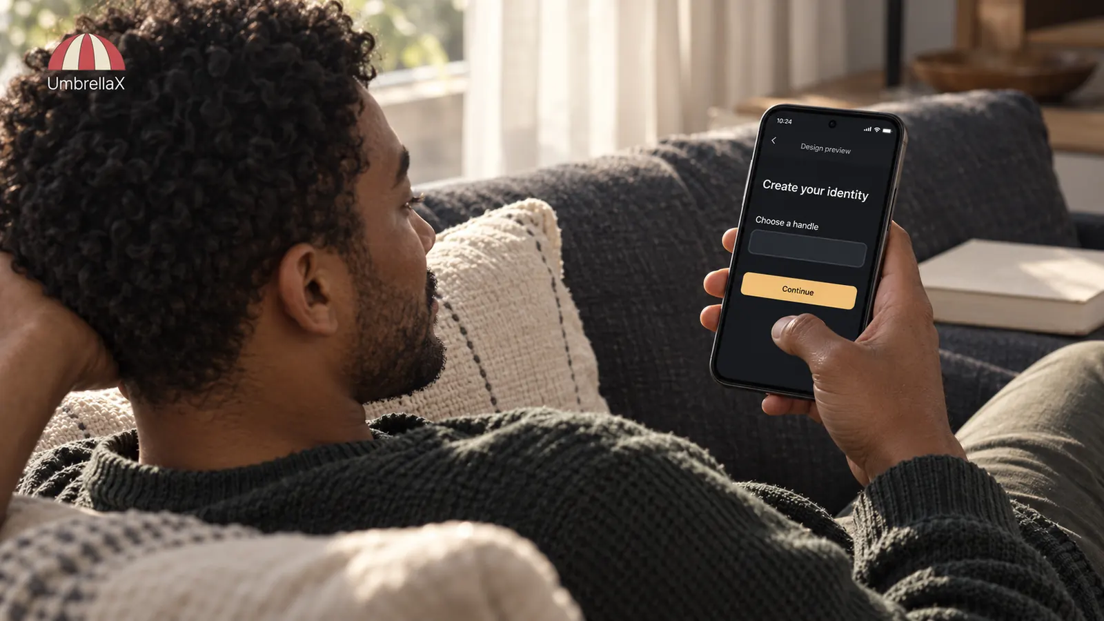 A person on a sofa tries a labelled identity-design preview with a handle and no phone-number field.